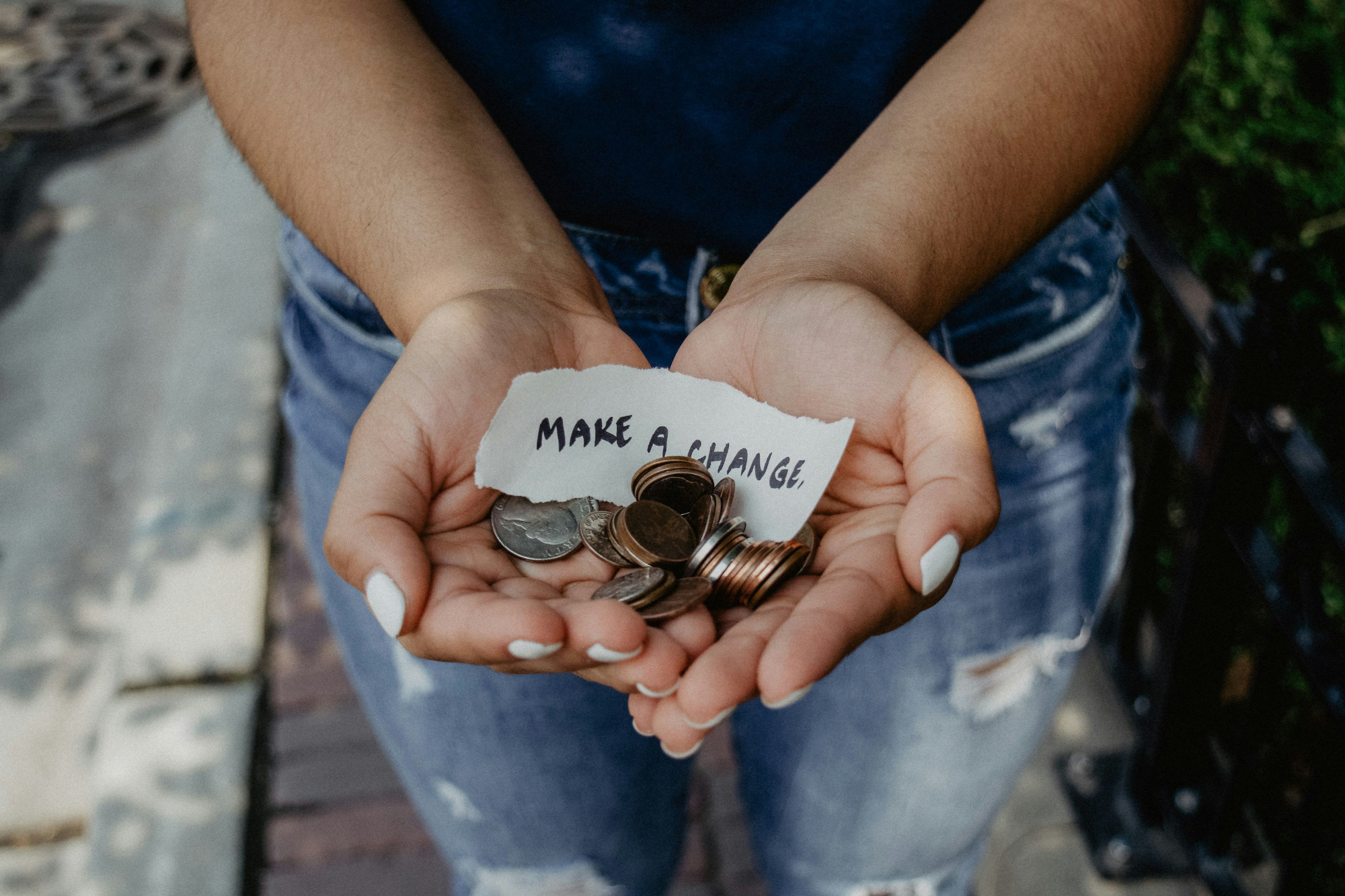 a pair of hands are extended, holding a collection of coins and a note that says "make a change"