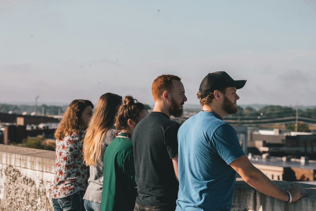 four people standing together leaning on concrete rails